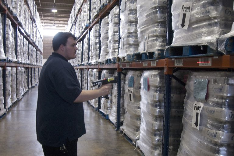 A worker among tall shelves in a logistics warehouse